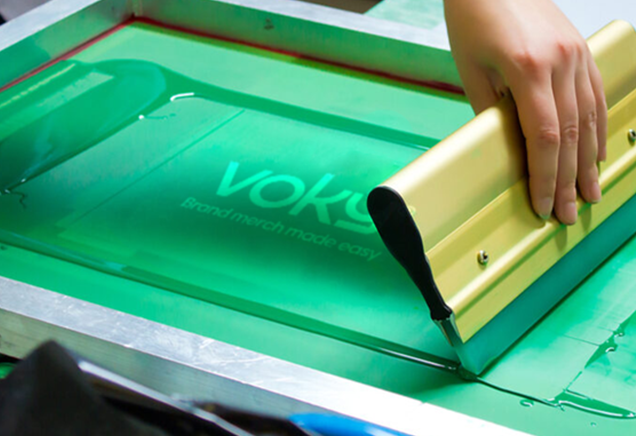 Voky-logotypen genomg&aring;r screentryck p&aring; en textil yta